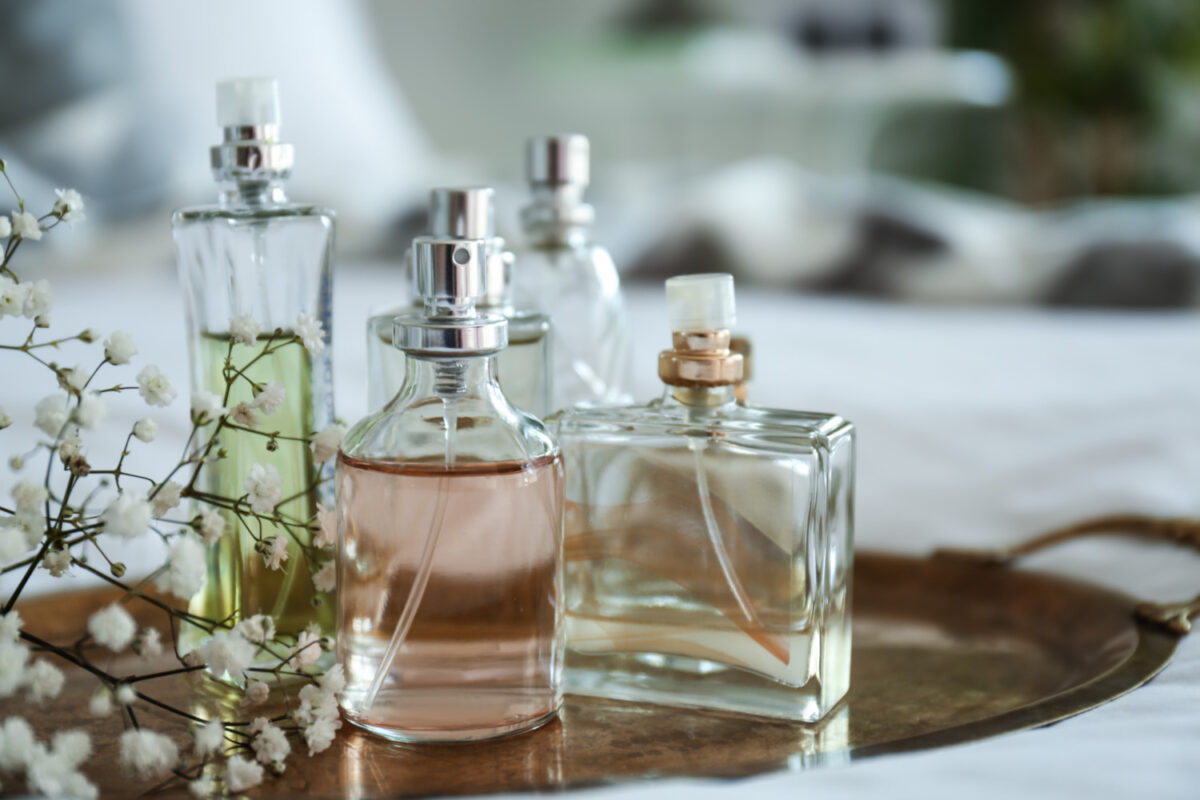 Bottles of perfume with flowers on metal tray